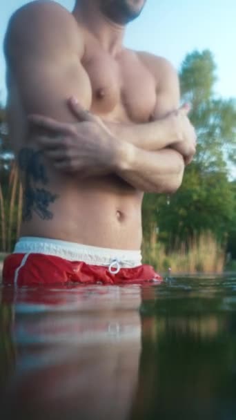 Frozen man plunges into icy water at morning. Male person chills and shakes inside cold winter lake at forest. Winter swim concept - Séquence, vidéo