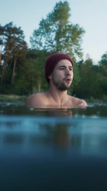 Serious man chills and shakes while standing inside cold winter lake at morning. Forest at the background. Winter swim and cold treatment concept - Séquence, vidéo