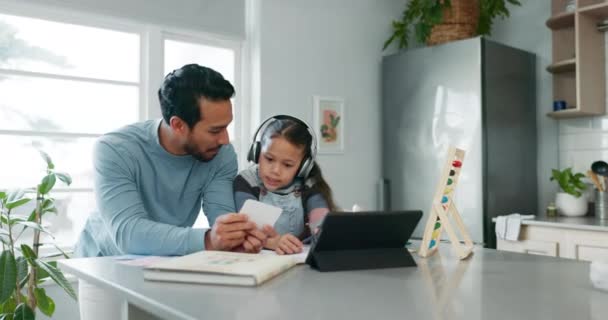 Helping with homework, dad and child with tablet, headphones and card learning, education and reading. Elearning, studying and father teaching girl at home school in kitchen for online class project - Footage, Video