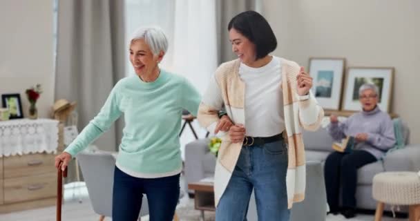 Dancing, senior woman and caregiver with happiness, music and freedom with retirement, energy or health. Female people, happy friends or ladies with movement, celebration or wellness in a living room. - Footage, Video