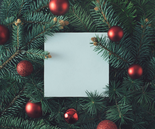 Kreatív elrendezés készült karácsonyfa ágak piros karácsonyi baubles és papír kártya jegyzetet. Lapos fekvés. Természet újévi koncepció. - Fotó, kép