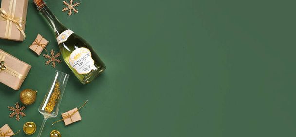 Komposition mit Flasche Champagner, Weihnachtsgeschenken und Dekorationen auf grünem Hintergrund mit Platz für Text - Foto, Bild