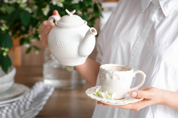 Kobieta przygotowuje herbatę z kwiatami jaśminu w kuchni, zbliżenie - Zdjęcie, obraz