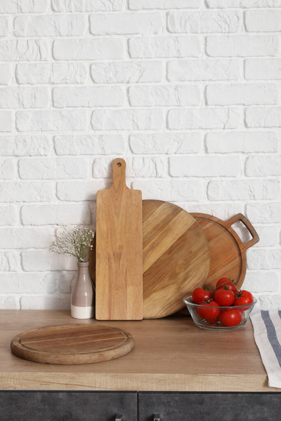 Wooden counter with cutting boards, fresh tomatoes and vase - Photo, Image