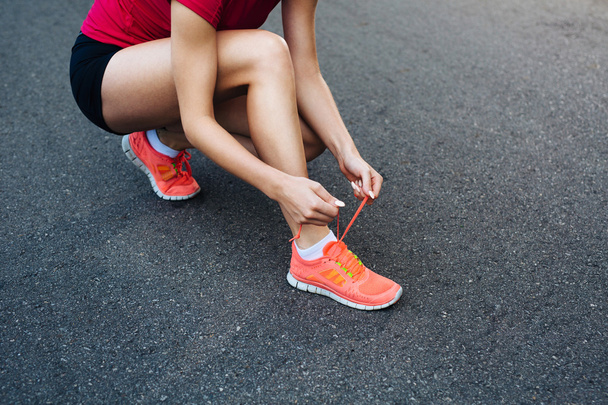 Female runner lacing her shoes - Foto, afbeelding