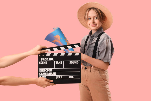 Petit acteur tenant carte et mains avec film clapper sur fond rose - Photo, image