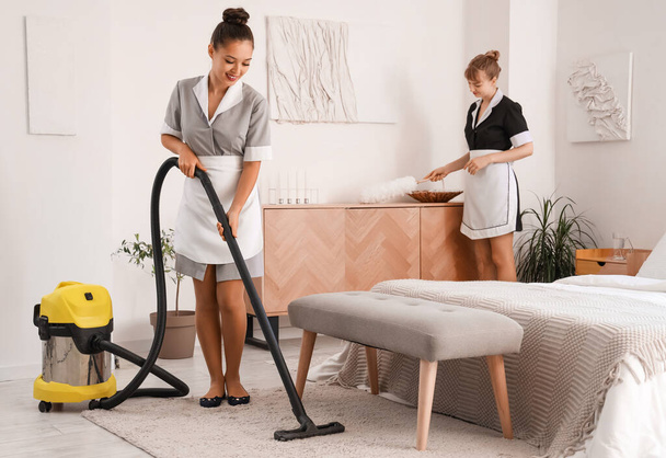 Pretty camareiras limpeza quarto de hotel com aspirador de pó - Foto, Imagem