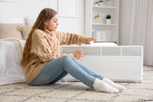 Frozen young woman with radiator in bedroom - Photo, Image