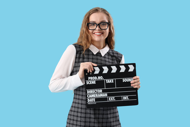 Schöne Schauspielerin mit Filmklöppel auf blauem Hintergrund - Foto, Bild