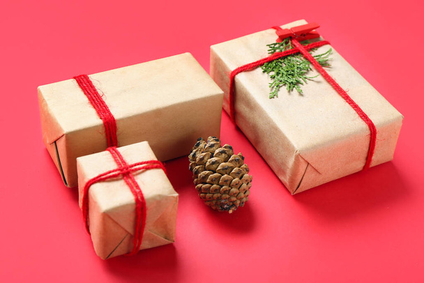 fenyőtoboz és karácsonyi ajándékdobozok piros alapon - Fotó, kép
