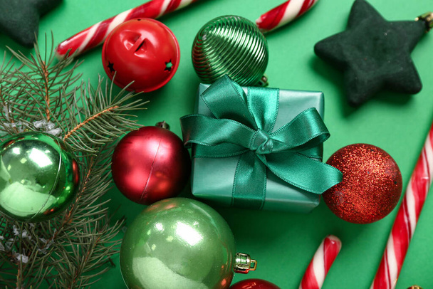 Bolas de Navidad con regalo, ramitas de abeto y bastones de caramelo sobre fondo verde - Foto, imagen
