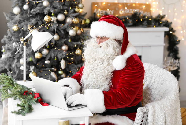 Санта Клаус использует ноутбук дома в канун Рождества - Фото, изображение
