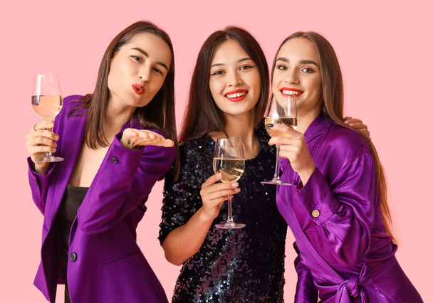 Young women with champagne on pink background. New Year celebration - Photo, Image