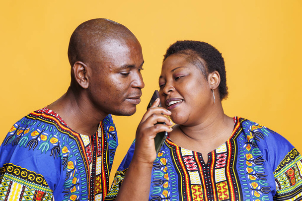Man en vrouw paar met behulp van mobiele telefoon als microfoon. Afrikaans-Amerikaanse zangers zingen samen in smartphone microfoon, opnemen lied met telefoon voice recorder toepassing - Foto, afbeelding