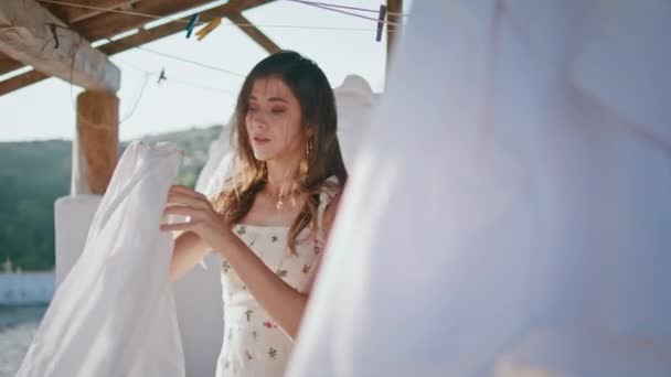 Brunette woman removing linen enjoying domestic routine alone at rural yard closeup. Romantic girl taking dry clothes at summer sunshine terrace. Sensual tender model folding laundry outdoors  - Footage, Video