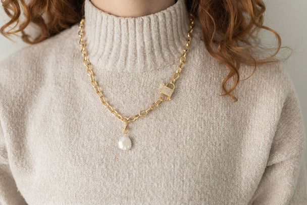 Close-up femminile in oro moderno collana catena in metallo con ciondolo di perle. - Foto, immagini