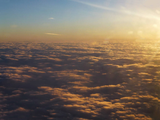 Άποψη του βραδινού ουρανού πάνω από τα σύννεφα και του ήλιου που δύει πίσω από τον ορίζοντα με τον μακρινό ορίζοντα - Φωτογραφία, εικόνα
