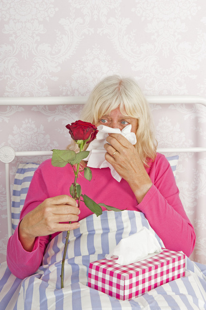 Mujer enferma en la cama con rosas y tejidos
 - Foto, imagen