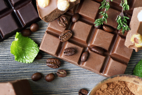 Набір шоколаду з горіхами, травами та кавовими зернами на дерев'яному столі, крупним планом
 - Фото, зображення