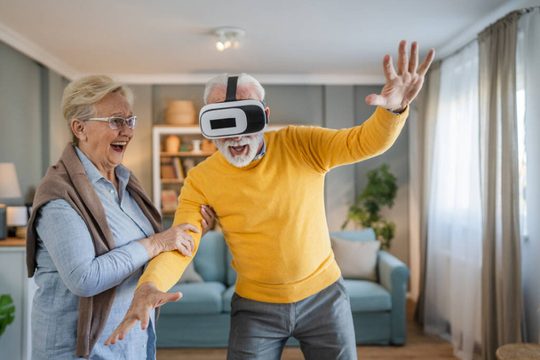 homme mature senior caucasien mâle mari avec sa femme senior couple à la maison profiter réalité virtuelle casque VR - Photo, image