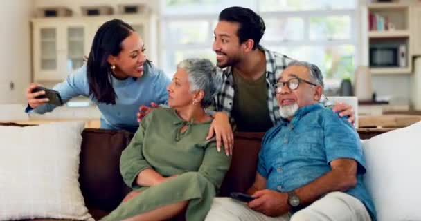 Family, selfie and senior couple relax on a sofa, bond and enjoy the weekend together in their home. Love, photo and adult siblings with elderly parents in living room for profile picture or memory. - Footage, Video