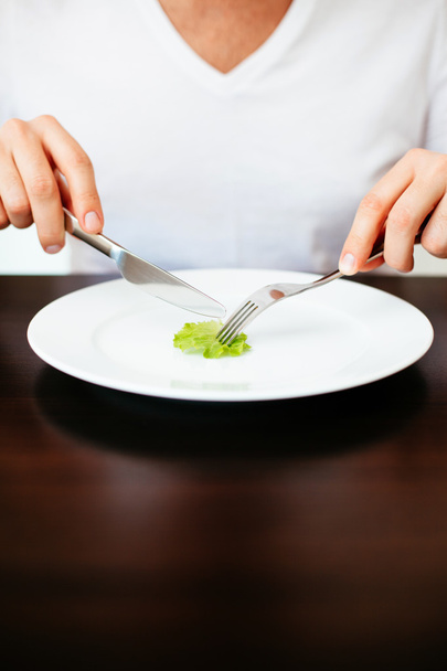 Man cutting a tiny piece of lettuce - Photo, image