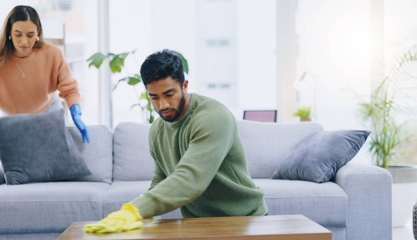 Couple, spring cleaning and gloves in home living room with teamwork for dirt, dust and bacteria with cloth. Man, woman and helping hand for furniture, hygiene and shine on wood with safety in house. - Photo, Image