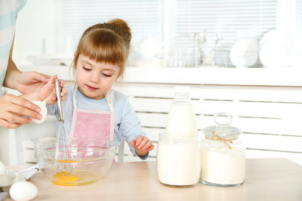 Little girl preparing cookies with  mother in kitchen at home - Photo, image