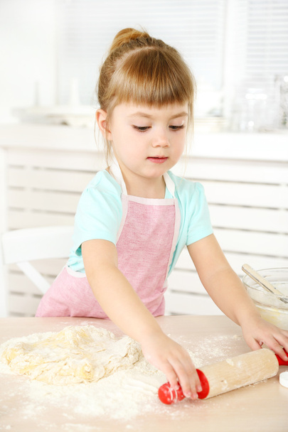 Little girl preparing cookies in kitchen at home - Fotó, kép