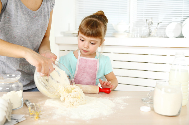 Little girl preparing cookies with  mother in kitchen at home - Foto, Bild