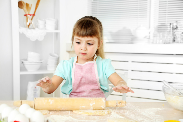 Little girl preparing cookies in kitchen at home - Фото, изображение