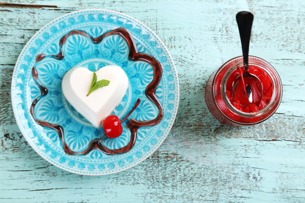 Tasty panna cotta dessert on plate, on wooden table - Foto, Imagen