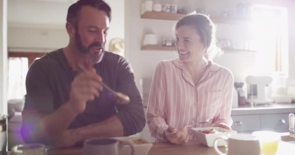 Šťastný pár, snídaně a smích s objetím v kuchyni pro legrační vtip, humor nebo meme při jídle doma. Muž a žena se usmívají a radostně se smějí za ranní komedii, cereálie nebo jídlo v domě. - Záběry, video