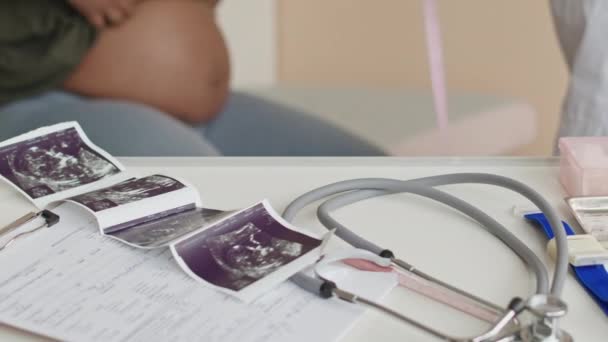 Tiro recortado de ginecologista feminino irreconhecível fazendo medições da barriga da mulher grávida na consulta de check-up médico com ultra-som do bebê na mesa em primeiro plano focado - Filmagem, Vídeo