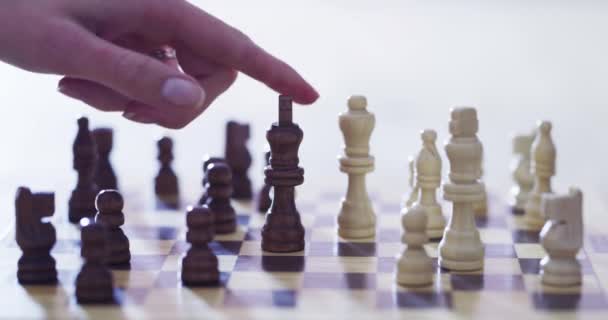 Käsi, shakki ja shakkimatti kanssa henkilö pelaa strategialautapeli lähikuva kotona vapaa. Mieli, aivot ja ajattelu, kun aikuinen liikuttaa kuningasta pöydällä kilpailun voittajana. - Materiaali, video