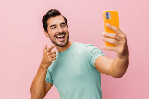 Мужчина улыбается телефон сообщение держа счастливый блог портрет мобильный трейдер студенческая студия скопировать успех бизнесмена бизнес-пространство киберпространство смартфон розовый фон общения образ жизни - Фото, изображение
