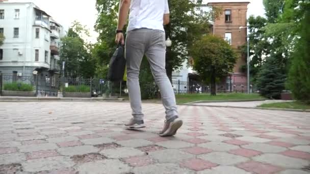 Nohy mladého muže v neformálním oblečení, který ráno běhá městským parkem. Podnikatel s taškou na běhání, protože pozdě do práce. Nepoznatelný chlap spěchající do kanceláře. Koncept dojíždění. Zpomalený pohyb. - Záběry, video