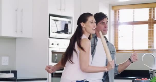 Home kitchen, dancing and couple singing routine, performance and excited fun, bonding and smile together. Rolling pin, music singer and marriage people freedom, support and dancer partner wellness. - Footage, Video
