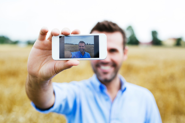 Man taking selfie in field - Zdjęcie, obraz
