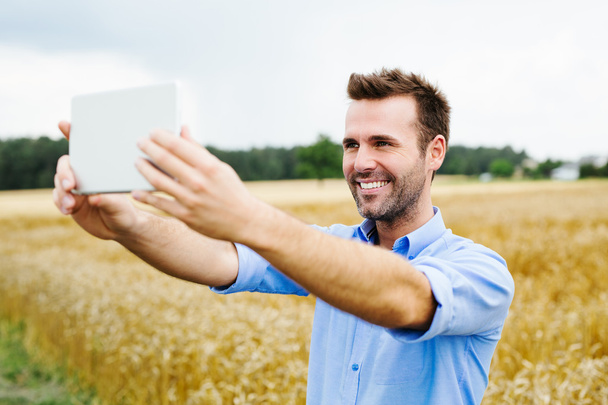 Man with digital tablet in field - Foto, afbeelding