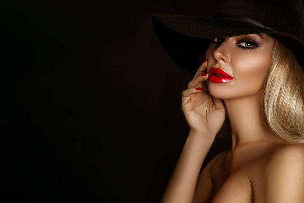 Zarif makyajlı, kırmızı dudaklı ve siyah arka planda şehvetli poz veren güzel bir kadın.. - Fotoğraf, Görsel