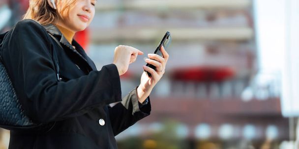 Sikeres üzletasszony játszik mobil szabadtéri. gyönyörű nő megy dolgozni okostelefonnal séta közelében irodaház. - Fotó, kép