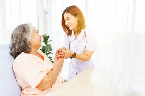 Médico femenino sostiene la mano anciana paciente mostrando expresiones positivas aliento buenos deseos unos a otros sanar enfermo normal saludable difundir la felicidad juntos en el hospital. - Foto, Imagen