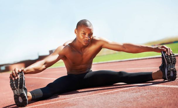 Ember, sportoló és nyújtózkodó lábak a padlón, szabadban és egészség, sport és teljesítmény. Fekete férfi személy, kész és bemelegítés a pályán, edzés és elkötelezettség a képzés, start és kardió. - Fotó, kép