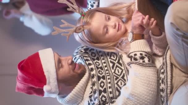 Valkoihoinen isä hänen söpö tytär harkitsee hauskoja kuvia kirjan istuessaan sohvalla. Ihmiset pukeutuvat jouluvaatteisiin ja lukevat mielenkiintoista tarinaa. Äänekkäästi nauraen yhteisen vapaa-ajan. - Materiaali, video
