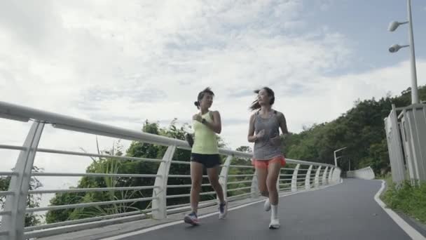 két fiatal ázsiai nő női barátok futás futás kocogás testmozgás szabadban a parkban - Felvétel, videó