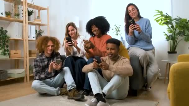 Gruppe junger Mitbewohner nutzt gemeinsam ihr Smartphone in Wohngemeinschaft. - Filmmaterial, Video