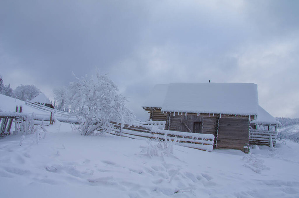 Ένα σπίτι στα χιονισμένα βουνά του χειμώνα. - Φωτογραφία, εικόνα
