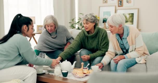 質の高い時間,チャット,または再会パーティーのためのホームソファーで話しているシニアの女性,お茶や友人. 高齢者や食料,社会訪問,退職生活のためのテーブルで介護者とグループ. - 映像、動画