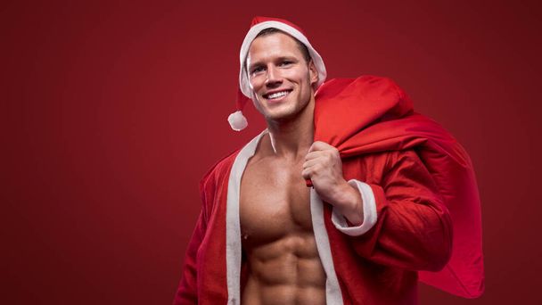 Fröhlicher Weihnachtsmann mit einem Sack über der Schulter, der Weihnachtsstimmung verbreitet - Foto, Bild